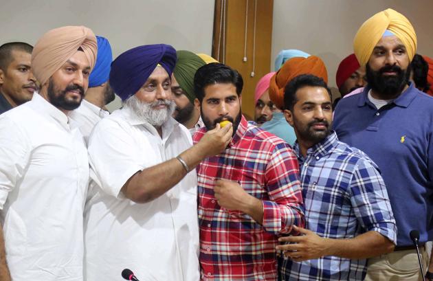 Shiromani Akali Dal president Sukhbir Singh Badal offering sweets to newly elected Panjab University Campus Students’ Council president Chetan Chaudhary in Chandigarh on Saturday.(HT Photo)