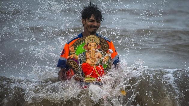 A devotee immerses an idol of Ganesh during the 5th day of the Ganesh Chaturthi festival, at Girgaon Chowpatty, in Mumbai, Maharashtra. (Pratik Chorge / HT Photo) A devotee immerses an idol of Ganesh during the 5th day of the Ganesh Chaturthi festival, at Girgaon Chowpatty, in Mumbai, Maharashtra. (Pratik Chorge / HT Photo)