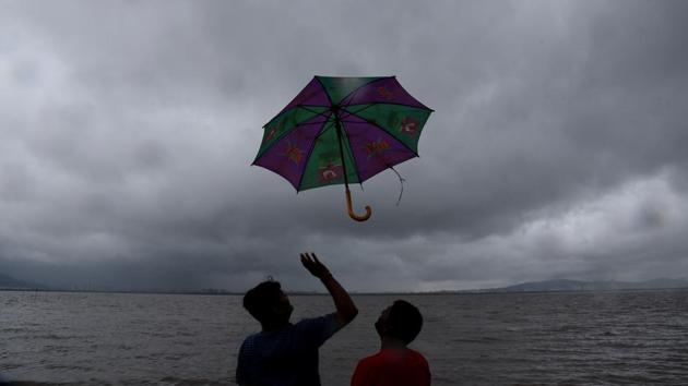 Men with an umbrella during high tide at Sagar Vihar Vashi in Navi Mumbai, Maharashtra. (Bachchan Kumar / HT Photo) Men with an umbrella during high tide at Sagar Vihar Vashi in Navi Mumbai, Maharashtra. (Bachchan Kumar / HT Photo)