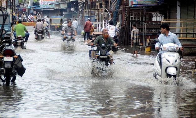 Commuters passing through the waterlogged street after heavy rain in Bhopal on Sunday. (Photo: ANI) Commuters passing through the waterlogged street after heavy rain in Bhopal on Sunday. (Photo: ANI)
