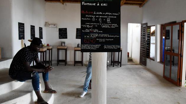 Thiaw sits next to a sign aimed at raising recycling awareness among customers. He felt powerless to act when he saw beaches where he played as a child turned into open waste heaps. His chance to take on the tide of trash came in 2016, when he took charge of this unpretentious little restaurant his father had opened on Le Virage beach in the 1970s. (Seyllou / AFP)
