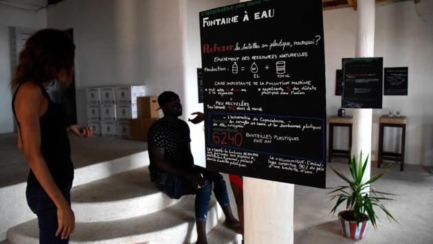 A woman reads a sensitisation sign calling people to recycle plastic. “The kids don’t understand -- they play with the rubbish just like balls,” said Mami Ndiaye, a regular customer at the Copacabana. (Seyllou / AFP)