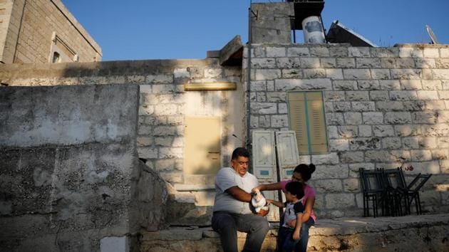 Palestinian farmer Azmi Musleh, 53, holds a rabbit as he spends time with his daughter and grandson in his yard in the village of Ein Yabrud. The red roofs of Ofra’s homes are easily seen from Ein Yabrud "That land is my heart and soul. It is my family's heart and soul. We used to grow sesame, figs, olives, back to the time of my father, his father, and his father before him," Musleh said. (Raneen Sawafta / REUTERS) Palestinian farmer Azmi Musleh, 53, holds a rabbit as he spends time with his daughter and grandson in his yard in the village of Ein Yabrud. The red roofs of Ofra’s homes are easily seen from Ein Yabrud "That land is my heart and soul. It is my family's heart and soul. We used to grow sesame, figs, olives, back to the time of my father, his father, and his father before him," Musleh said. (Raneen Sawafta / REUTERS)