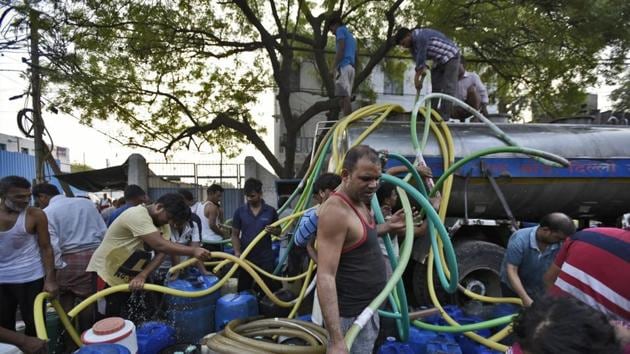 Delhi government’s scheme of providing 20,000 litres of water each month free of cost to every household in the national capital is being misused by several housing colonies. Here, in Okhla, residents form a line of buckets and containers to receive water from tankers.(HT FILE)