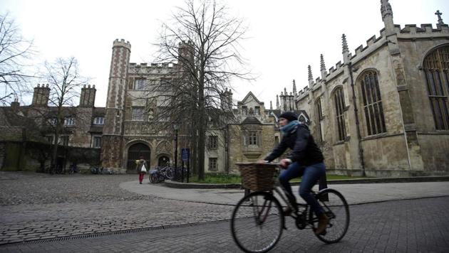 A cyclist rides a bicycle past Trinity College, part of the University of Cambridge, in Cambridge, U.K.(Bloomberg Photo)