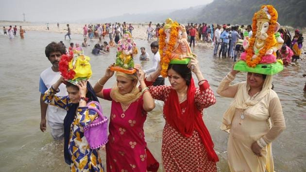 Women carry idols of Ganesha on their heads as they enter the Tawi River during ‘Anant Chaturdashi’ celebrations, in Jammu city. (PTI) 