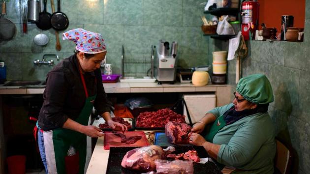 Women prep a meal at the soup kitchen. Argentines have seen their earnings, savings and purchasing power diminished. “I don’t have any dollars, what can they do for me? There are other basic needs I have to find a solution for,” says Aiva. “We must give priority to other things, to pay the day to day, to eat every day,” the 48-year-old activist adds. (Ronaldo Schemidt / AFP)