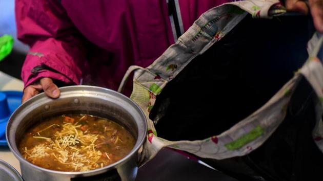 A woman prepares a takeaway pot with food at the soup kitchen. Municipal authorities supply enough meat and vegetables every day to make 160 meals, but the women say they manage to stretch their supplies out to feed 200. The IMF is expected to disburse the latest tranche of the loan, $5.4 billion, this month. (Ronaldo Schemidt / AFP)