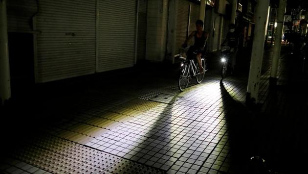 Men ride bicycles along a sidewalk during a blackout caused by Typhoon Faxai near a train station in Kisarazu, Chiba prefecture, Japan. (Issei Kato / REUTERS) Men ride bicycles along a sidewalk during a blackout caused by Typhoon Faxai near a train station in Kisarazu, Chiba prefecture, Japan. (Issei Kato / REUTERS)
