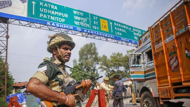 A BSF jawan guards as Jammu and Kashmir Police personnel check the vehicles on the Jammu-Srinagar highway after a truck was seized with arms and ammunition, in Kathua.(PTI)