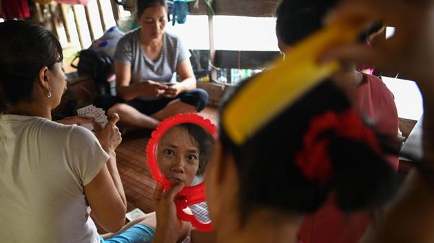 A Vietnamese migrant worker living in a floating guesthouse along the banks of the Red River in Hanoi, combs her hair as others play cards after the end of a day's work. Card games and karaoke help these workers pass the time on the cramped houseboats of the Red River, swapping their privacy to eke out a living selling fruit for a few dollars a day. (Manan Vatsyayana / AFP) A Vietnamese migrant worker living in a floating guesthouse along the banks of the Red River in Hanoi, combs her hair as others play cards after the end of a day's work. Card games and karaoke help these workers pass the time on the cramped houseboats of the Red River, swapping their privacy to eke out a living selling fruit for a few dollars a day. (Manan Vatsyayana / AFP)