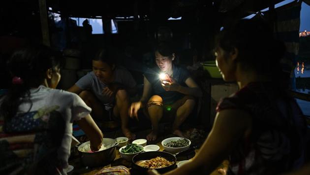 A migrant worker uses the torch light of her mobile phone as a group eats dinner at sunset. Every year, more than 260,000 migrants stream into Hanoi and the southern megacity of Ho Chi Minh City to study or work. Many take up temporary jobs in construction or as housekeepers, nannies and traders. (Manan Vatsyayana / AFP) A migrant worker uses the torch light of her mobile phone as a group eats dinner at sunset. Every year, more than 260,000 migrants stream into Hanoi and the southern megacity of Ho Chi Minh City to study or work. Many take up temporary jobs in construction or as housekeepers, nannies and traders. (Manan Vatsyayana / AFP)