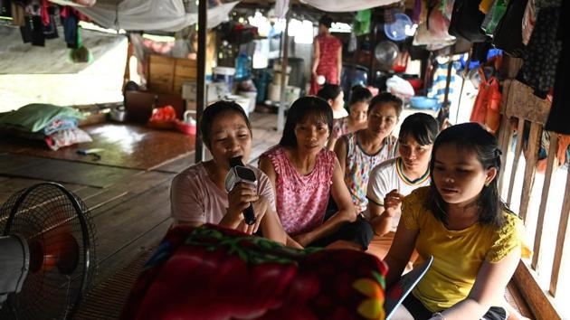 Nguyen Thi Hang (L), a migrant worker living for the past seven years in a floating guesthouse, singing karaoke along with other workers. But for many of the workers living on the Red River, the flexibility and camaraderie that comes with selling fruit brings fragments of comfort. (Manan Vatsyayana / AFP) Nguyen Thi Hang (L), a migrant worker living for the past seven years in a floating guesthouse, singing karaoke along with other workers. But for many of the workers living on the Red River, the flexibility and camaraderie that comes with selling fruit brings fragments of comfort. (Manan Vatsyayana / AFP)