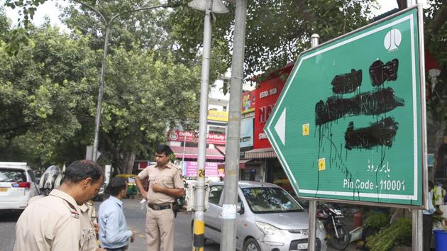 Police personnel stand beside the blackened signboard for Babar Road in New Delhi on Saturday. Right-wing outfit Hindu Sena blackened the signage in Bengali market demanding that it be renamed.(PTI PHOTO.)