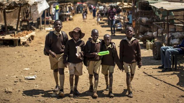 Schoolboys walk back home on the first day of the school term, in Kuwadzana, on the outskirts of the capital Harare. A city of 1.5 million, bustles with activities of people scraping by, including street traders selling second-hand clothes, people striding to work past faded murals of Mugabe and women carrying baskets of laundry they had just washed in a muddy creek. (Ben Curtis / AP) 