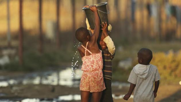 Girls carrying buckets of water on their heads, people praying at sunset, children in uniforms going to their first day of the new school term. Shortages of electricity, water, fuel and cash are the latest symptoms of Zimbabwe's economic decline that began in 2000 when Mugabe launched the seizures of farms owned by whites. (Tsvangirayi Mukwazhi / AP) 