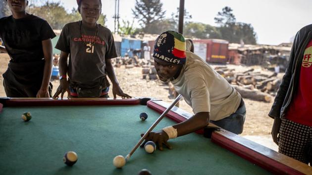 Young men play a game of pool in the open air in Norton, west of the Harare. But life in the capital is not all work. Children play on swings and unemployed young men wile away their time playing pool and drinking potent, and illegal, home brew. (Ben Curtis / AP) 