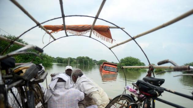 Boatmen pass by a dumper truck stuck on a road submerged with floodwaters of the Ganges river at Badara Sanuti village, near Prayagraj, in Uttar Pradesh. (Sanjay Kanojia / AFP)