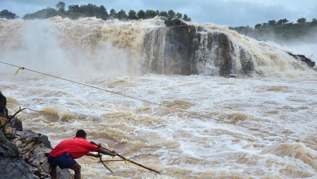 A fisherman uses a net attached to sticks to catch fish in rough waters next to Dhuandhar Falls following heavy rainfall, at Narmada River, in Jabalpur, Madhya Pradesh. (Shankar Mishra / AFP)