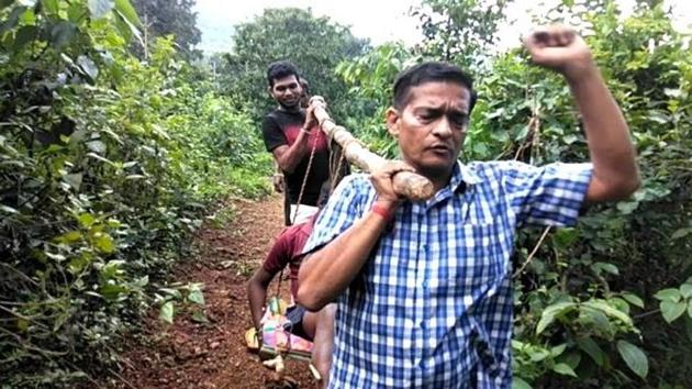 Shakti Prasad Mishra, a 52-year-old doctor working in a sub-centre in Khairput block of Malkangiri district, carried a 12-year-old orphaned boy in a sling and walked for 5 km in hilly and forested terrains(HT Photo)