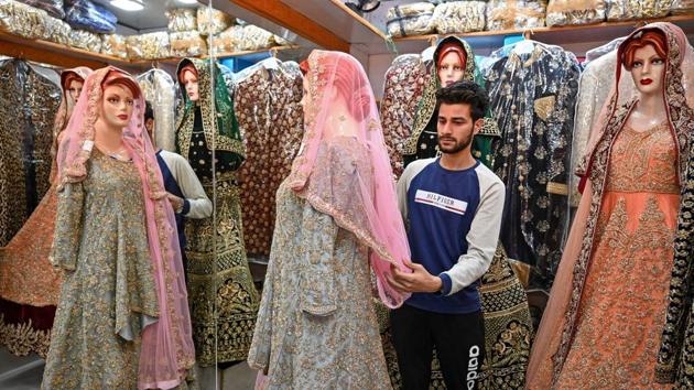 A Kashmiri shopkeeper displays wedding dresses at a market in Srinagar. The heavily militarised region is no stranger to security crackdowns. But this time, even the usually buoyant wedding industry -- a major driver of Kashmir’s economy -- is buckling under the strain, with hundreds of notices appearing in newspapers and on television in recent weeks, postponing or cancelling ceremonies. (Tauseef Mustafa / AFP)