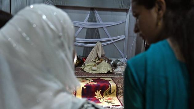 Guests look at a bride (C) with her face and body covered with a shawl sits in her new husband's home following their marriage. For bride-to-be Nisar, her September wedding to her boyfriend of five years came after a hard-fought battle with their parents to overcome resistance to the marriage. (Tauseef Mustafa / AFP)