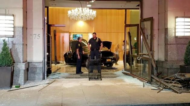 Police officers stand near a car after it crashed into the lobby of the Trump Plaza in New Rochelle, New York, US.(JOSE ABARCA VIA REUTERS) Police officers stand near a car after it crashed into the lobby of the Trump Plaza in New Rochelle, New York, US.(JOSE ABARCA VIA REUTERS)