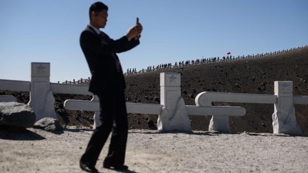 A security guard takes a photo as a group of North Korean students march to the summit of Mount Paektu. For ordinary workers it can be a two- or three-day trip, but for students the standard itinerary is four weeks, officials said, including a period of voluntary work on a construction site or other project. (Ed Jones / AFP) A security guard takes a photo as a group of North Korean students march to the summit of Mount Paektu. For ordinary workers it can be a two- or three-day trip, but for students the standard itinerary is four weeks, officials said, including a period of voluntary work on a construction site or other project. (Ed Jones / AFP)
