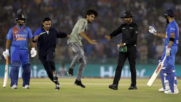 A security personnel, second from left, tries to stop a fan of India's captain Virat Kohli after he ran towards the pitch during the second T20 international match between India and South Africa, in Mohali(AP)