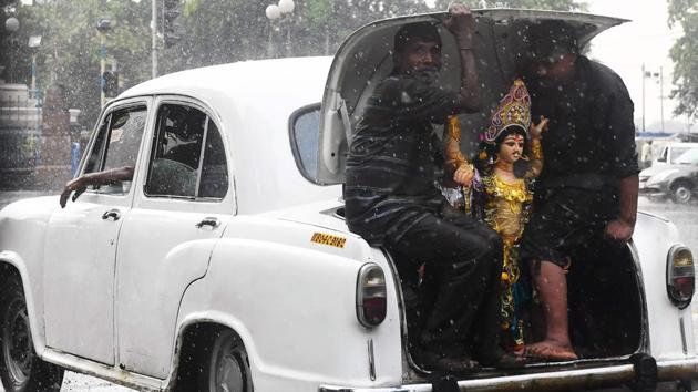 Devotees sit in the boot of a Hindustan Ambassador car with an idol of the Hindu deity Vishwakarma as they transport it in the rain for an immersion ceremony in Kolkata, West Bengal. (Dibyangshu Sarkar / AFP) Devotees sit in the boot of a Hindustan Ambassador car with an idol of the Hindu deity Vishwakarma as they transport it in the rain for an immersion ceremony in Kolkata, West Bengal. (Dibyangshu Sarkar / AFP)