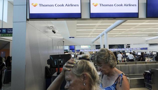 Stranded tourists walk past a Thomas Cook counter at the Cancun airport in Mexico. British tour company Thomas Cook collapsed early Monday after failing to secure emergency funding, leaving tens of thousands of vacationers stranded abroad.(AP)