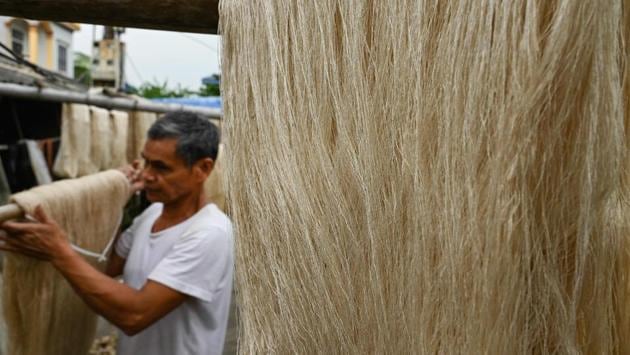 White silk thread yarns are hung out to dry as Pham Van Ba, 56, carries ones that have dried. “Our products will be ruined” if it’s not dried under the sun, he told AFP, explaining that even good quality thread can be marred by inclement weather. (Manan Vatsyayana / AFP)