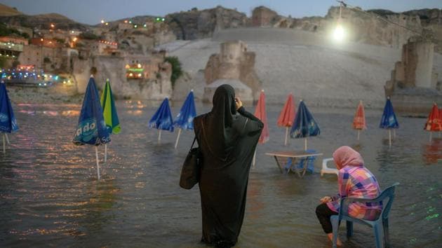 A woman takes a picture of Hasankeyf, on the banks of the Tigris. At first glance all is as normal in this Turkish town which as seen the Romans, Byzantines, Turkic tribes and Ottomans leave their mark over its 12,000 years of inhabitation. But Hasankeyf is disappearing. An artificial lake, part of the Ilisu hydroelectric dam project, is swallowing it up. The dam, which will be Turkey’s second largest, has been built further downstream the Tigris. (Bulent Kilic / AFP)