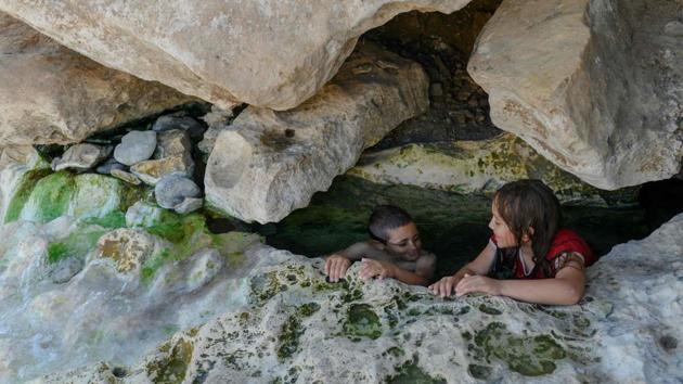 Muhammed (L) and Hasret (R) enjoy a hot spring water in the Botan valley a few kilometers from the Ilisu dam, next to the city of Siirt. The flooding is forcing local fishermen, used to working the flowing waters of the Tigris, to adapt to still waters. Halil Ertan, 48, isn’t impressed by the new types of fish he finds in the lake -- fatter and less tasty, he said. (Bulent Kilic / AFP)