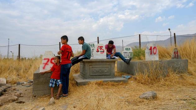 Back at the graveyard, Yunus (2nd-L) stoods with his younger brother (L) as they waited for workers to show them the grave of their younger baby brother who died at birth in 2016. But when he found it, the officials told him the family has not done the necessary paperwork for the grave to be moved. (Bulent Kilic / AFP)