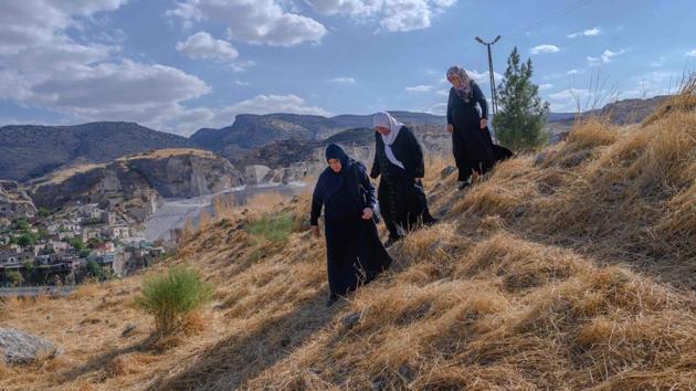 Hacire Yalcin (C), 55-years-old walks with her sister and her sister in-law (R) in the middle of old Hasankeyf cemetery as they search for one of their relatives' graves which will be moved to the new Hasankeyf cemetery. They are among the lucky ones; the graves of those like Yunus’s brother will be submerged with everything else that is left behind. (Bulent Kilic / AFP)