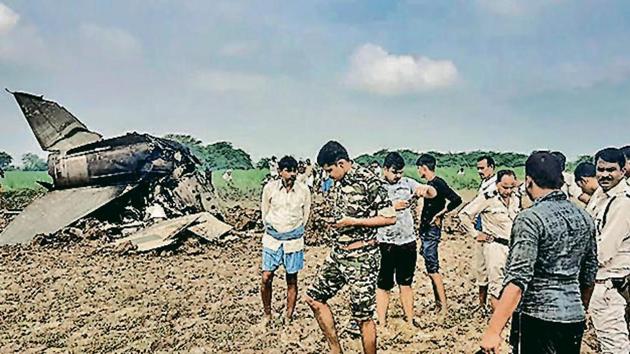 Policemen and locals gather at the site where MiG-21 trainer jet crashed near the Gwalior airbase on Wednesday.(PTI)