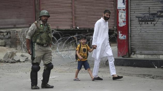 A man walks with a child past a paramilitary soldier standing guard during restrictions ahead of Friday prayers in Srinagar. Normal life in the valley has remained crippled since August 5, when the Centre revoked Jammu and Kashmir’s special status under Article 370 and announced the decision to bifurcate the state into two Union territories. The government has deployed thousands of troops to the already heavily militarized region to quell potential dissent. (Mukhtar Khan / AP) A man walks with a child past a paramilitary soldier standing guard during restrictions ahead of Friday prayers in Srinagar. Normal life in the valley has remained crippled since August 5, when the Centre revoked Jammu and Kashmir’s special status under Article 370 and announced the decision to bifurcate the state into two Union territories. The government has deployed thousands of troops to the already heavily militarized region to quell potential dissent. (Mukhtar Khan / AP)