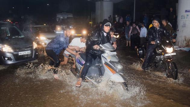 Passers-by push a two-wheeler stuck in floodwaters amid heavy rain, in Pune city on Wednesday. Pune, which is around 200 kilometres from Mumbai, has received 113% more rainfall than average since the start of the monsoon season in early June, a weather department official said. Intense showers battered Pune city and parts of the district on Wednesday and Thursday. (PTI) Passers-by push a two-wheeler stuck in floodwaters amid heavy rain, in Pune city on Wednesday. Pune, which is around 200 kilometres from Mumbai, has received 113% more rainfall than average since the start of the monsoon season in early June, a weather department official said. Intense showers battered Pune city and parts of the district on Wednesday and Thursday. (PTI)