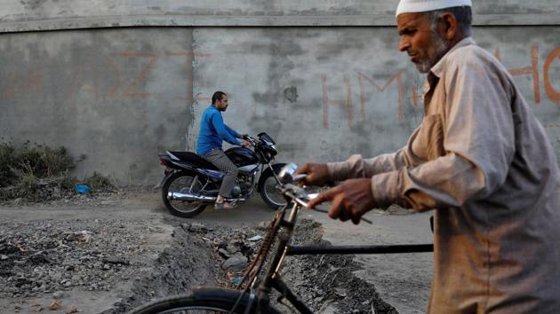 Men ride past a trench dug by residents to prevent security forces from entering Anchar neighbourhood. Residents have set up improvised barricades made up from tree trunks, electricity poles and barbed wires, and dug up the lanes to stop the advance of the security forces vehicles. (Danish Siddiqui / REUTERS)