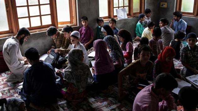 College students teach children inside a house in Anchar neighbourhood. Four college students have set up a makeshift school in a three-room house to give lessons to 200 children for a few hours each day. They keep streaming in, the girls with their heads covered, books in hand from nursery rhymes to mathematics. (Danish Siddiqui / REUTERS)