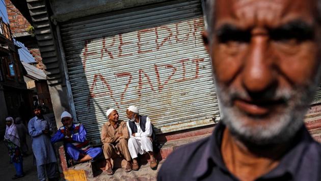 Men sit in front of the pro-independence graffiti sprayed on the shutter of a closed shop in the main square in Anchar neighbourhood. The government cut internet and mobile services and imposed curfew-like restrictions to prevent protests. More than seven weeks later, some normalcy has returned and many of those detained have since been freed. (Danish Siddiqui / REUTERS)