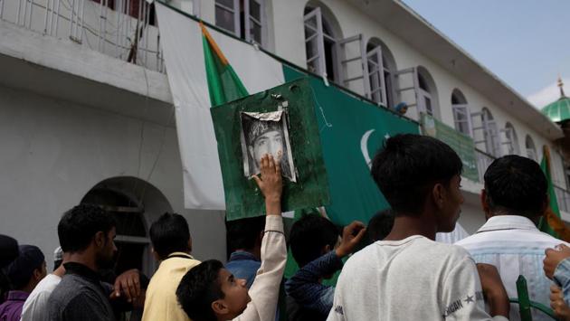 A Kashmiri boy touches the photo of Burhan Wani, a dead militant commander, as others participate in a protest at Jinab Sahib mosque. Anchar remains a no-go zone for security forces, and government services like schools are still shut in the area, prompting residents to come up with workarounds. (Danish Siddiqui / REUTERS)