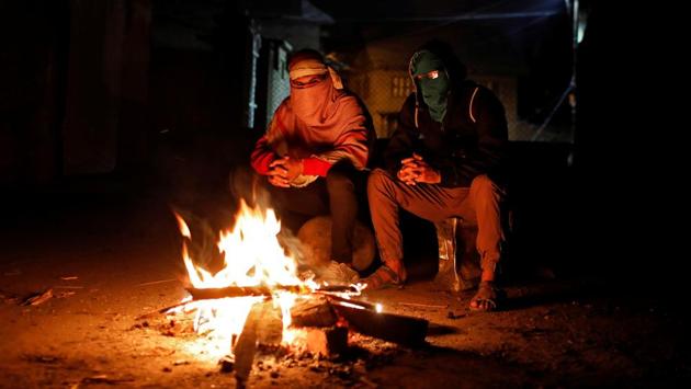 As night falls, groups of youths, many wearing masks and armed with stones and tree branches, are huddled around bonfires, sipping tea provided by neighbours. They keep vigil in fear that the police will enter their homes. (Danish Siddiqui / REUTERS)
