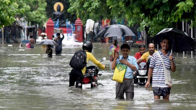 People wade through a flooded street aftert heavy rainfall in Patna on Saturday.(ANI PHOTO.)
