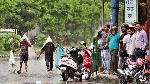 People take shelter during heavy rain in Jammu on Saturday.(PTI)