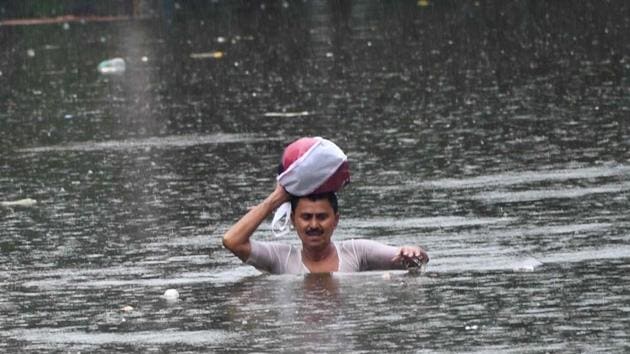 A man wades through a flooded street after heavy rainfall in Patna on Sunday. (ANI PhoTO)