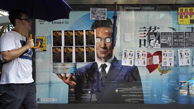 A man holding an umbrella walks by a bus stop advertisement filled with protest art posters. All summer, young people in Hong Kong have been buying dozens of cans of spray paint with their pocket money and taking to the streets, turning their hometown into a canvas of anti-government graffiti. (Vincent Yu / AP) A man holding an umbrella walks by a bus stop advertisement filled with protest art posters. All summer, young people in Hong Kong have been buying dozens of cans of spray paint with their pocket money and taking to the streets, turning their hometown into a canvas of anti-government graffiti. (Vincent Yu / AP)