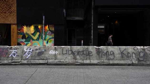 A man walks by the road block with anti-government graffiti. The most common graffiti is "Liberate Hong Kong, Revolution of Our Times." Other messages include the popular chant "Five Demands and Not One Less," expressing demands for greater democracy, and the trending hashtag “Chinazi,” a portmanteau of China and Nazi. (Vincent Yu / AP) A man walks by the road block with anti-government graffiti. The most common graffiti is "Liberate Hong Kong, Revolution of Our Times." Other messages include the popular chant "Five Demands and Not One Less," expressing demands for greater democracy, and the trending hashtag “Chinazi,” a portmanteau of China and Nazi. (Vincent Yu / AP)