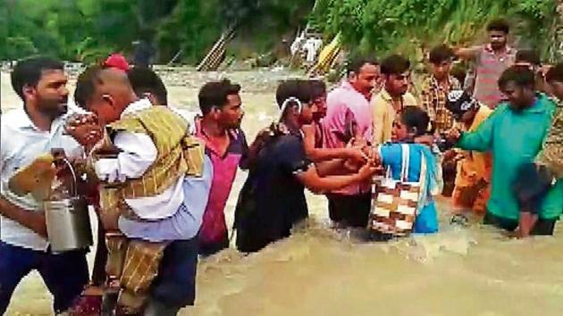 Pilgrims cross a flooded street after the flash flood at Shakumbhari Devi temple in Saharanpur on Sunday, (R) a view of a waterlogged street outside Adampur police station following heavy rains, in Varanasi on Sunday.(ANI Photo)